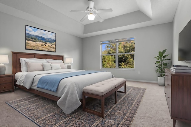 carpeted bedroom featuring a raised ceiling and ceiling fan