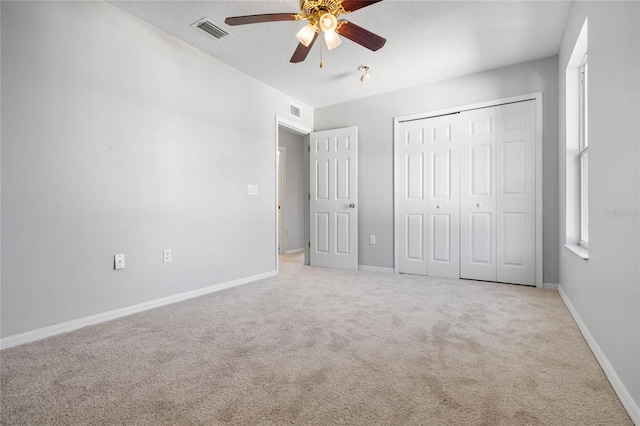 unfurnished bedroom featuring a closet, ceiling fan, light carpet, and a textured ceiling