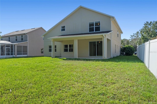 rear view of property with a sunroom and a lawn