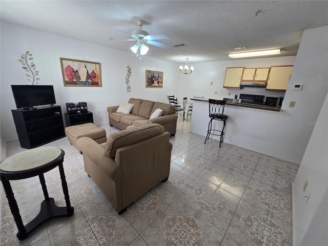 living room featuring a textured ceiling and ceiling fan with notable chandelier