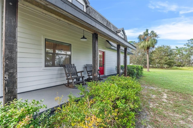 view of exterior entry featuring covered porch and a yard