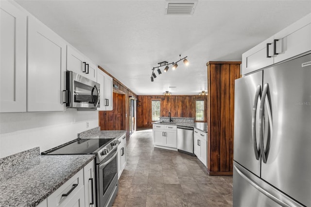 kitchen with dark stone counters, sink, a textured ceiling, white cabinetry, and stainless steel appliances