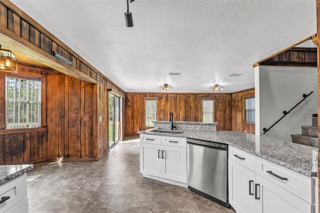 965 Keen Rd, Frostproof, FL 33843 - kitchen featuring dishwasher, wooden walls, healthy amount of natural light, a sink, and a textured ceiling