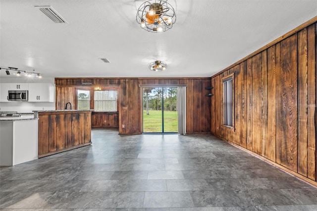 unfurnished living room with wooden walls and a textured ceiling