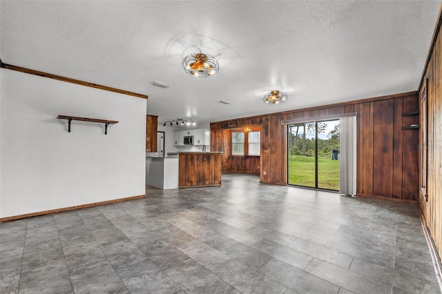 965 Keen Rd, Frostproof, FL 33843 - unfurnished living room featuring wood walls, a textured ceiling, and baseboards