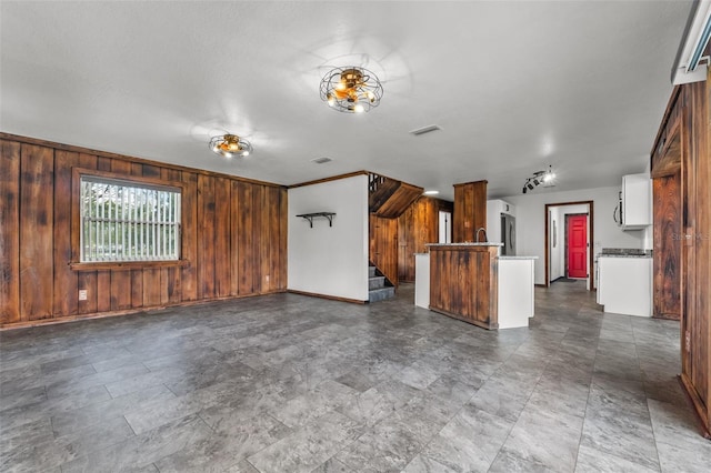 unfurnished living room with wood walls and ornamental molding