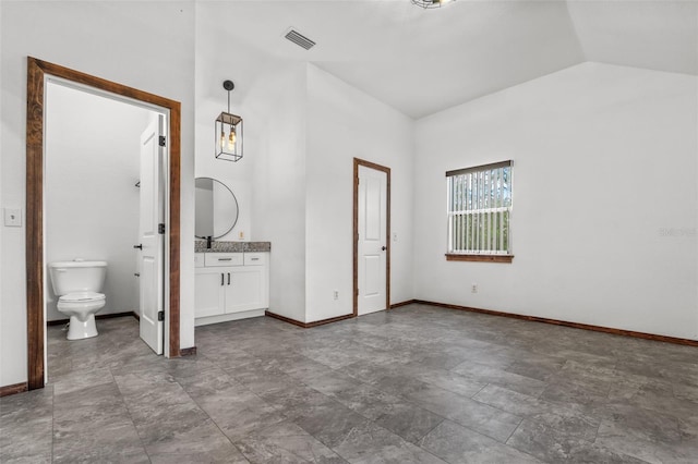 unfurnished bedroom with ensuite bathroom and vaulted ceiling