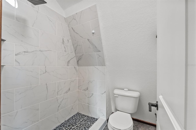 bathroom with a tile shower and toilet