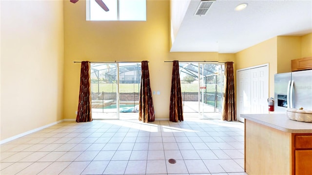 interior space featuring light tile patterned floors, stainless steel fridge, and plenty of natural light