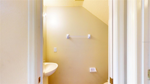 bathroom with toilet, sink, and vaulted ceiling