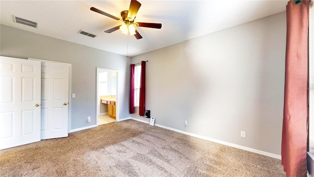 unfurnished bedroom with ceiling fan, ensuite bath, and light carpet