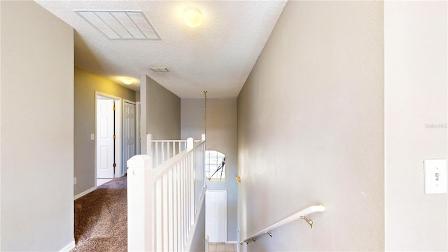 hallway with a textured ceiling and carpet floors