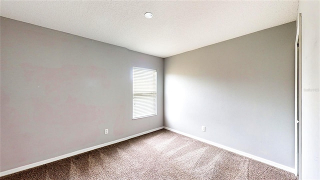 carpeted empty room featuring a textured ceiling