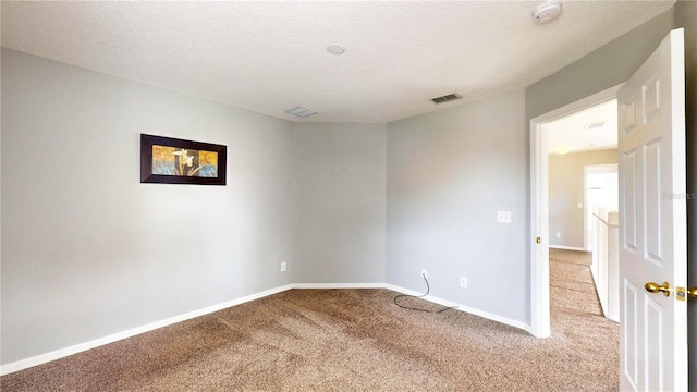 empty room featuring a textured ceiling and light carpet