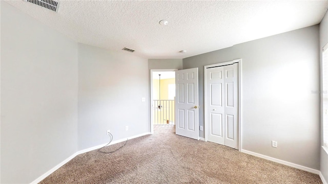 unfurnished bedroom with carpet, a textured ceiling, and a closet