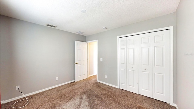 unfurnished bedroom featuring a closet, a textured ceiling, and carpet flooring