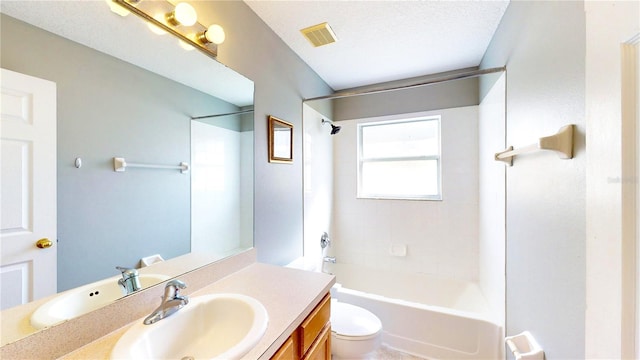 full bathroom featuring vanity, toilet, a textured ceiling, and tiled shower / bath combo