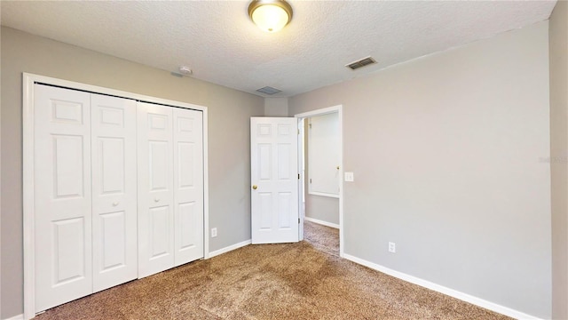 unfurnished bedroom with carpet, a textured ceiling, and a closet