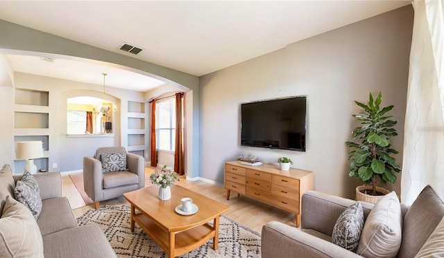 living room featuring built in features and light hardwood / wood-style floors