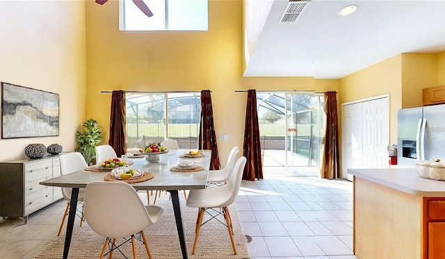 tiled dining room with ceiling fan, a towering ceiling, and a healthy amount of sunlight