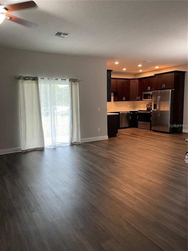 unfurnished living room with ceiling fan, a textured ceiling, and dark hardwood / wood-style flooring