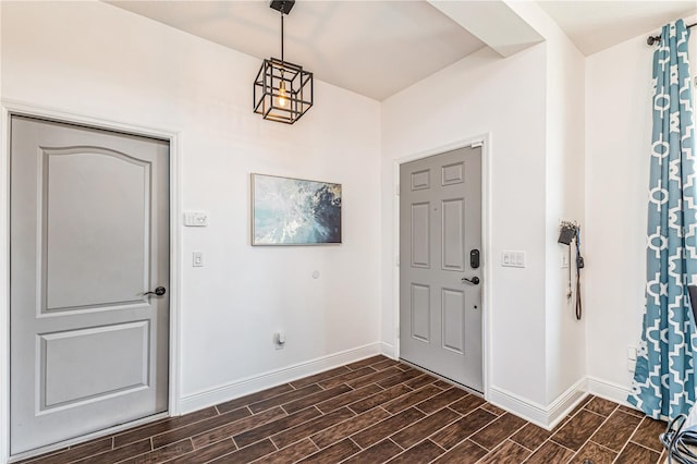 foyer with dark wood-type flooring and a notable chandelier