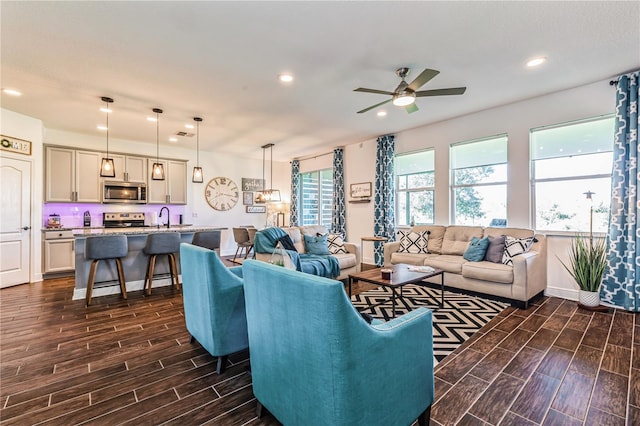 living room featuring dark wood-type flooring, ceiling fan, and sink