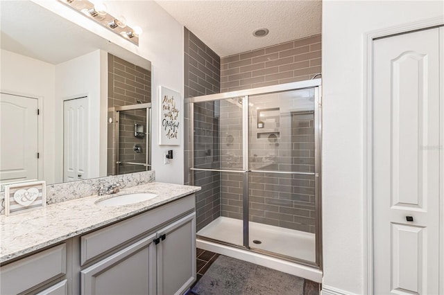 bathroom featuring vanity, a textured ceiling, and a shower with door