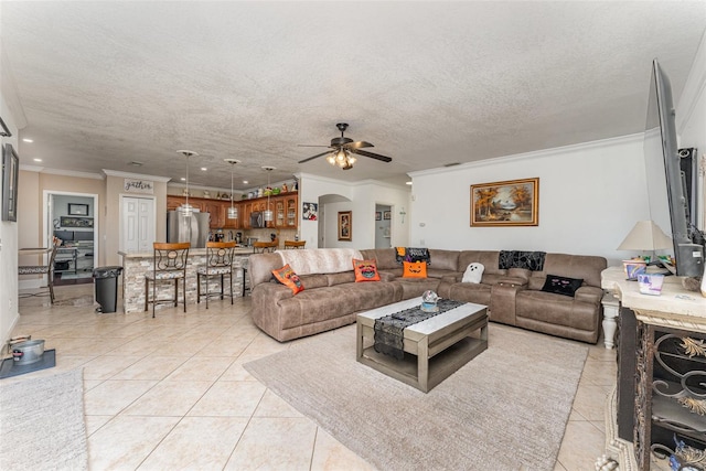 living room with ceiling fan, a textured ceiling, light tile patterned flooring, and ornamental molding