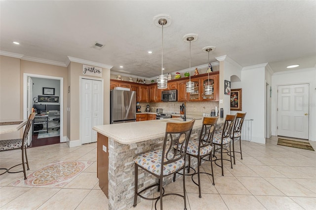 kitchen featuring kitchen peninsula, stainless steel appliances, ornamental molding, and a kitchen bar