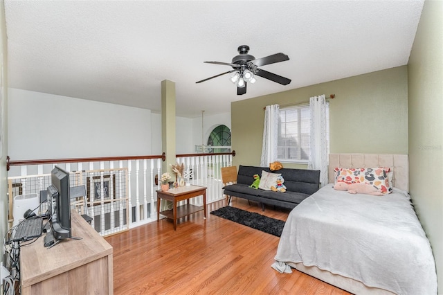 bedroom with light hardwood / wood-style flooring, a textured ceiling, and ceiling fan