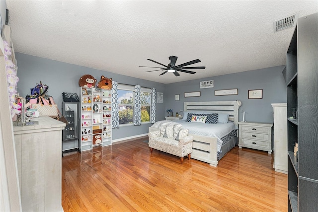 bedroom with ceiling fan, a textured ceiling, and hardwood / wood-style floors