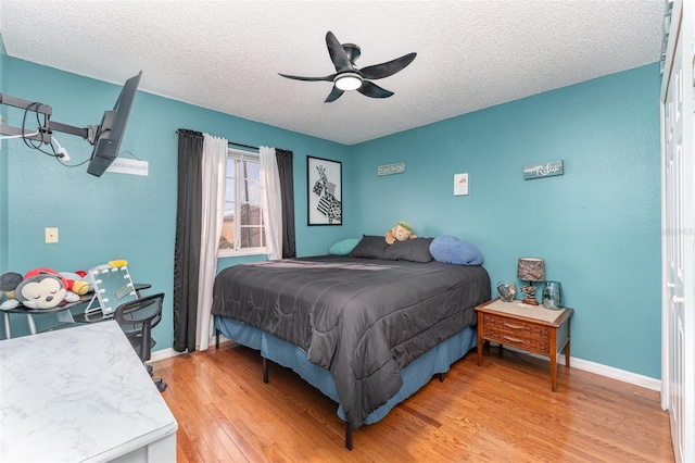 bedroom with ceiling fan, a textured ceiling, and light hardwood / wood-style flooring