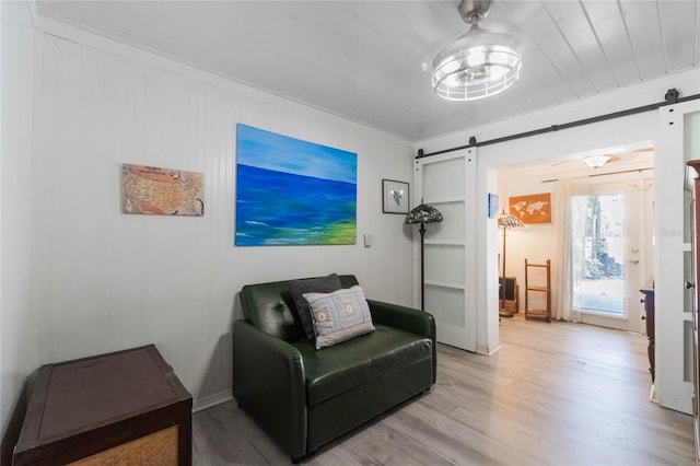 sitting room featuring ornamental molding, a barn door, and light hardwood / wood-style floors