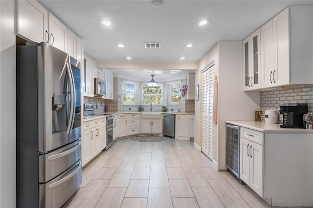 kitchen with stainless steel appliances, tasteful backsplash, wine cooler, and white cabinets