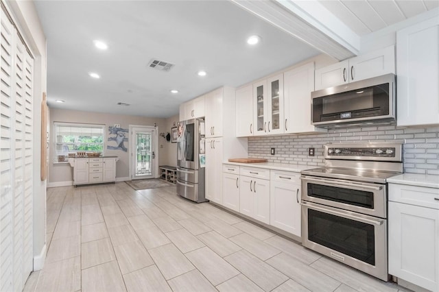 kitchen with backsplash, stainless steel appliances, and white cabinets