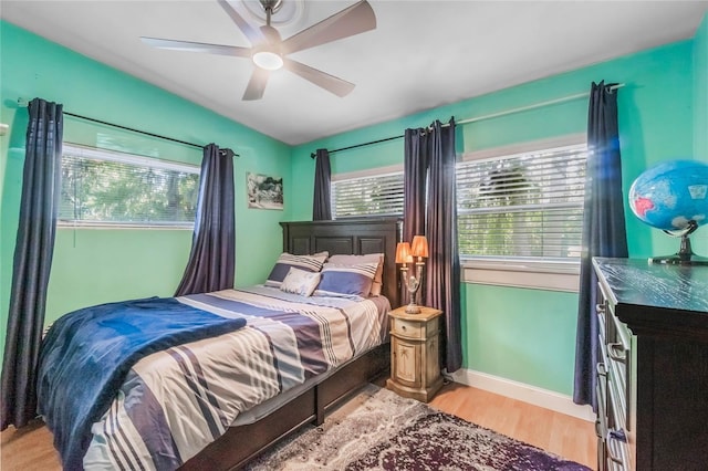 bedroom featuring ceiling fan, multiple windows, and light wood-type flooring