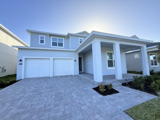 view of front facade with an attached garage, decorative driveway, and stucco siding