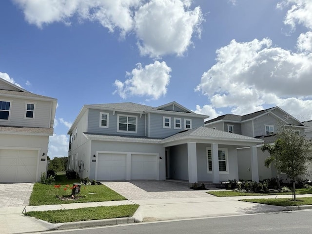 view of front of home featuring a residential view, decorative driveway, roof with shingles, and an attached garage