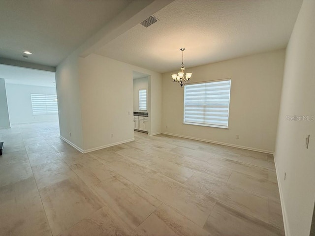 empty room with an inviting chandelier, visible vents, and baseboards