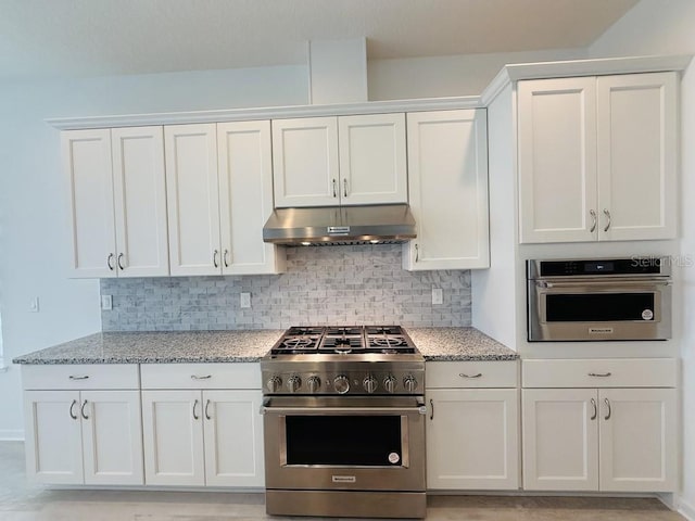 kitchen with stainless steel appliances, white cabinets, under cabinet range hood, and light stone counters