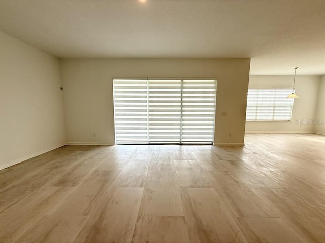 empty room with light wood-type flooring and baseboards