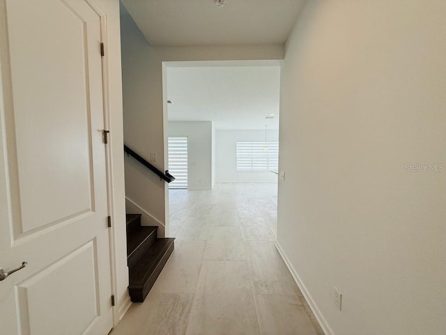 hallway featuring stairs and baseboards