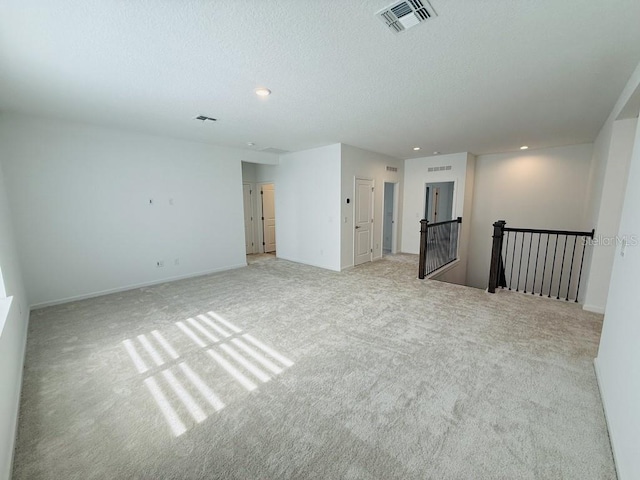 empty room featuring light carpet, recessed lighting, visible vents, and a textured ceiling