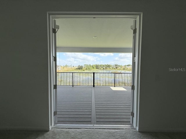 doorway featuring a water view, carpet flooring, and baseboards