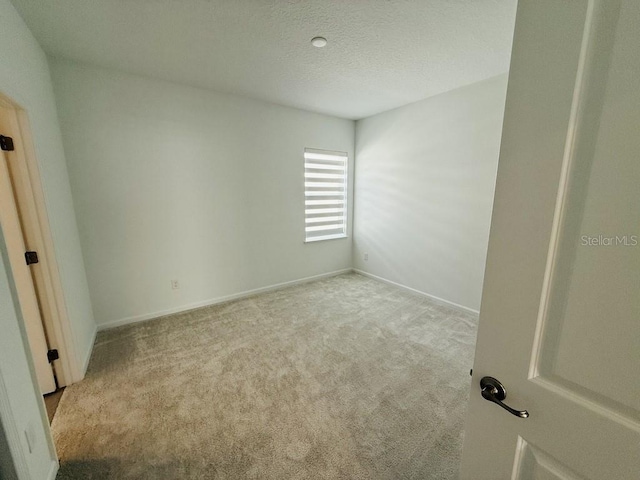 unfurnished bedroom with baseboards, a textured ceiling, and light colored carpet