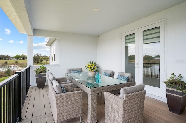 balcony with outdoor dining space and a water view