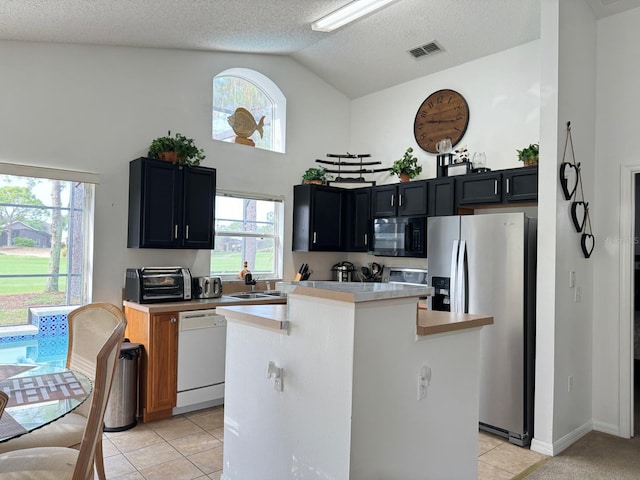 kitchen featuring a wealth of natural light, white dishwasher, a kitchen island, and stainless steel fridge