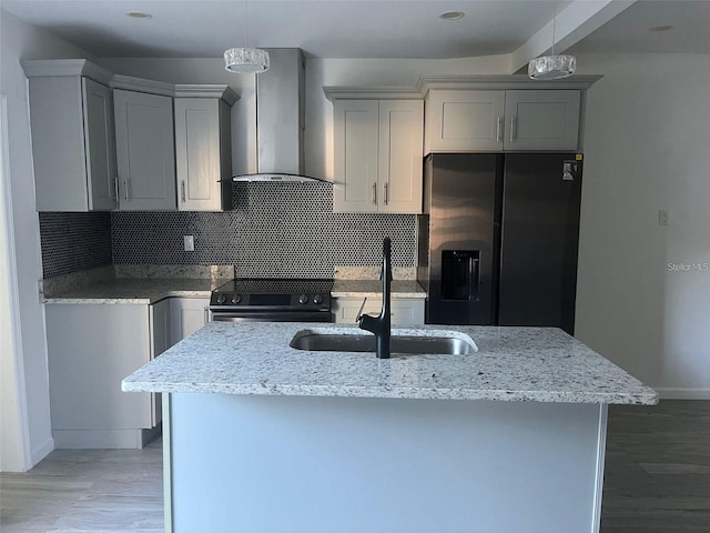 kitchen with wall chimney range hood, a center island with sink, sink, black appliances, and light stone counters