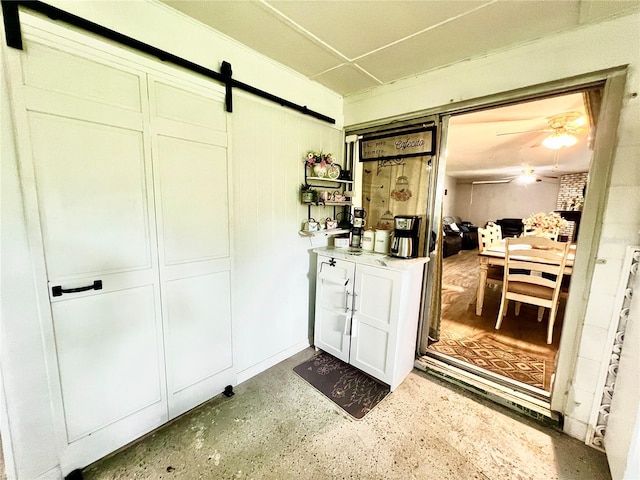 interior space with a barn door and ceiling fan